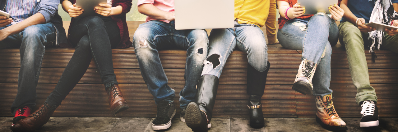 Advice for Starting University With a Disability Students with laptops sitting on a bench.