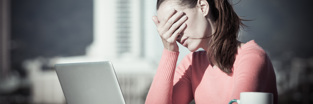 When Checking for Symptoms Is an OCD Symptom woman stressed by computer covering eyes with hand