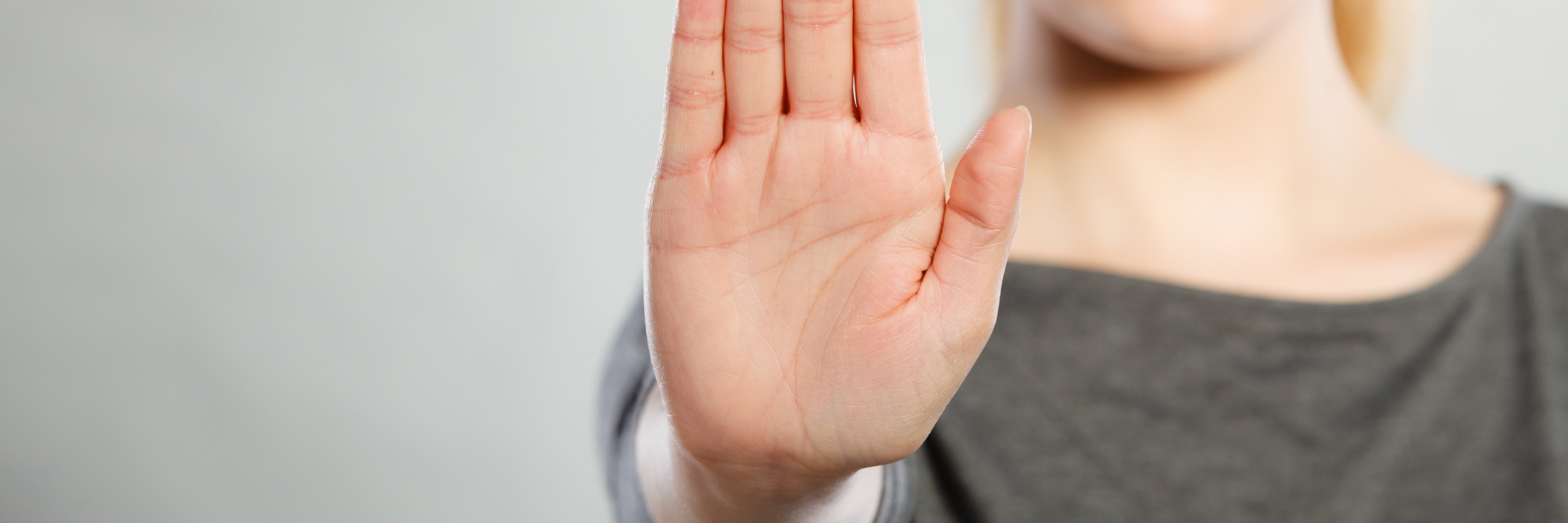 Assertiveness Training: An Important Weapon in BPD Recovery assertive looking woman holding up hand in stop gesture against plain gray background