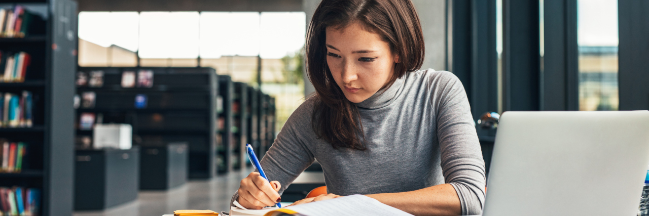 5 Messages for My Fellow Anxious Students Starting College Female student taking notes from a book at library. Young asian woman sitting at table doing assignments in college library.