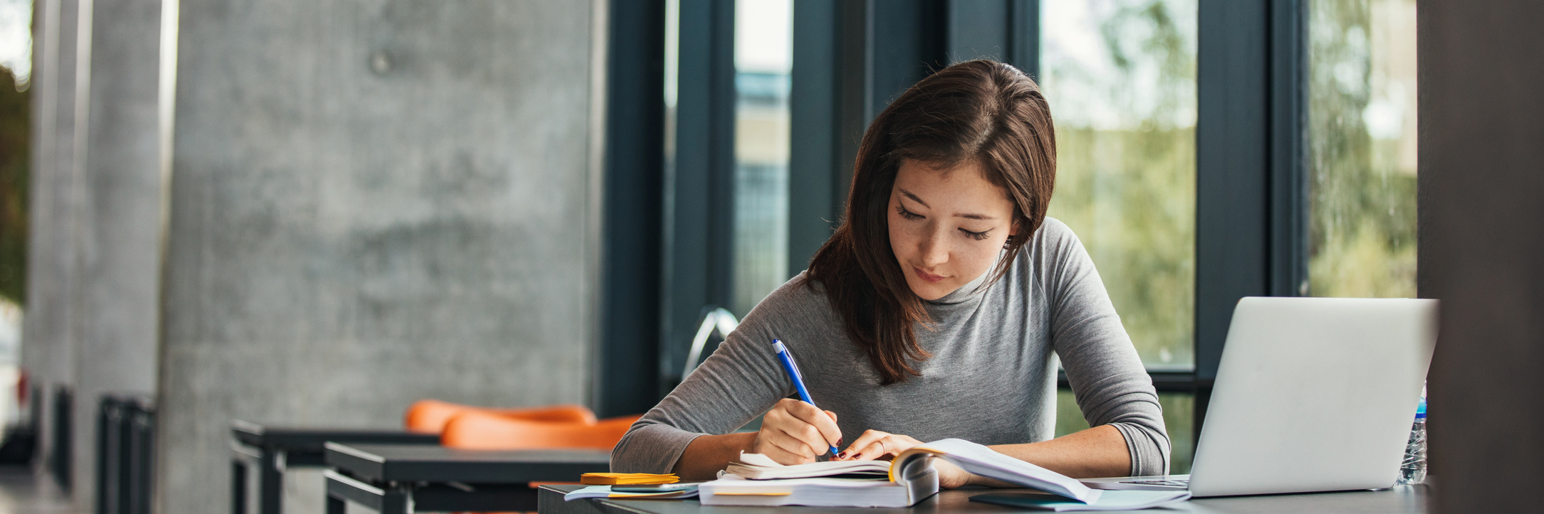 Shot of young asian female student sitting at table and writing on notebook. Young female student studying in library.