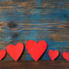red heart shapes in line on wooden background