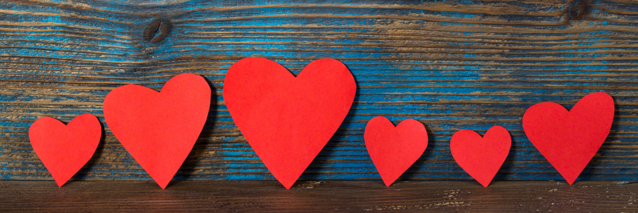 What It's Like to Be a Spouse to Someone With DID red heart shapes in line on wooden background