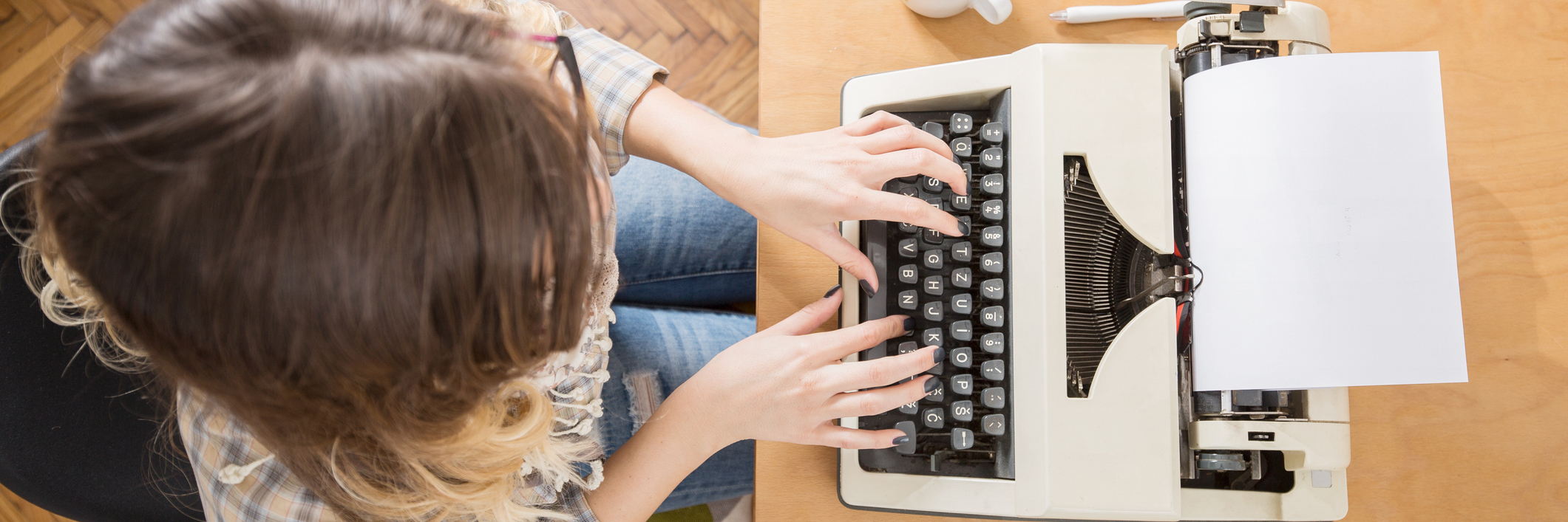 A Letter to the Person Diagnosed With Hidradenitis Suppurativa A woman writing on a typewriter with her phone and coffee by her side.
