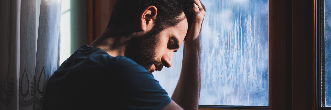 What to Do When Your Anxiety Manifests as Anger young angry man sitting at window with head on hand