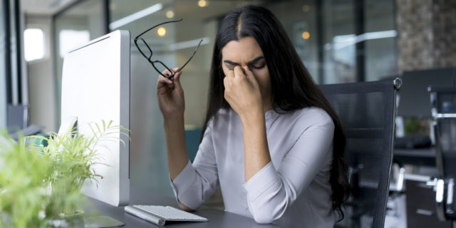 tired woman rubbing her eyes while working