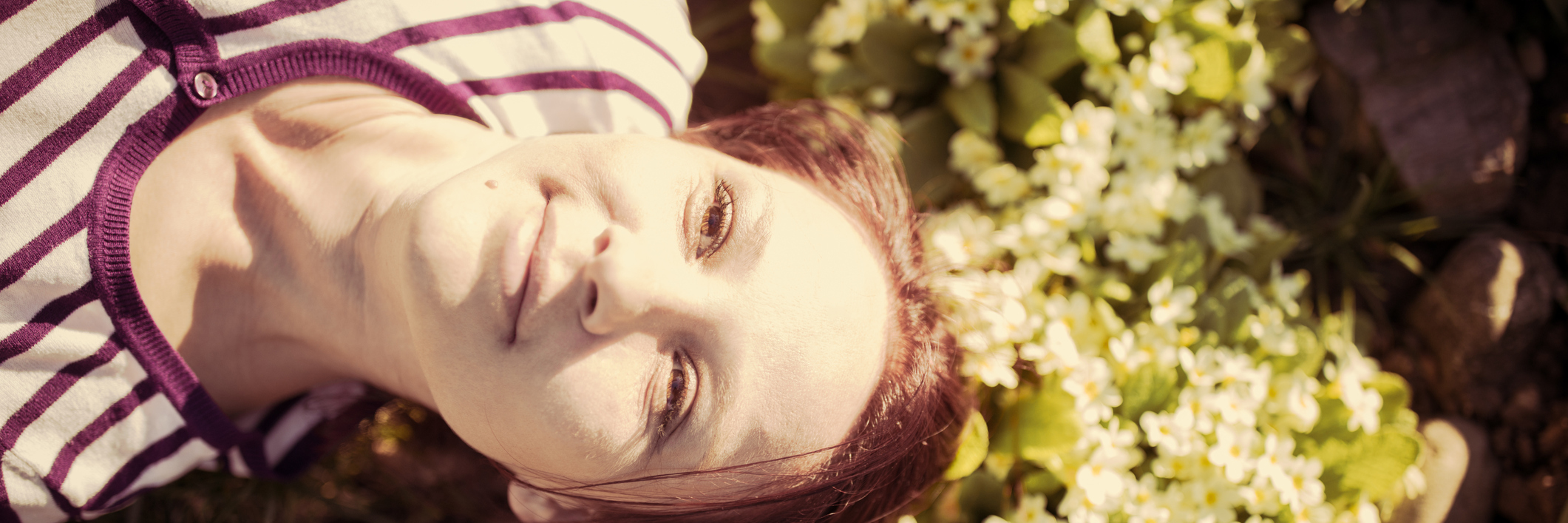 young woman lying in sunny garden looking content