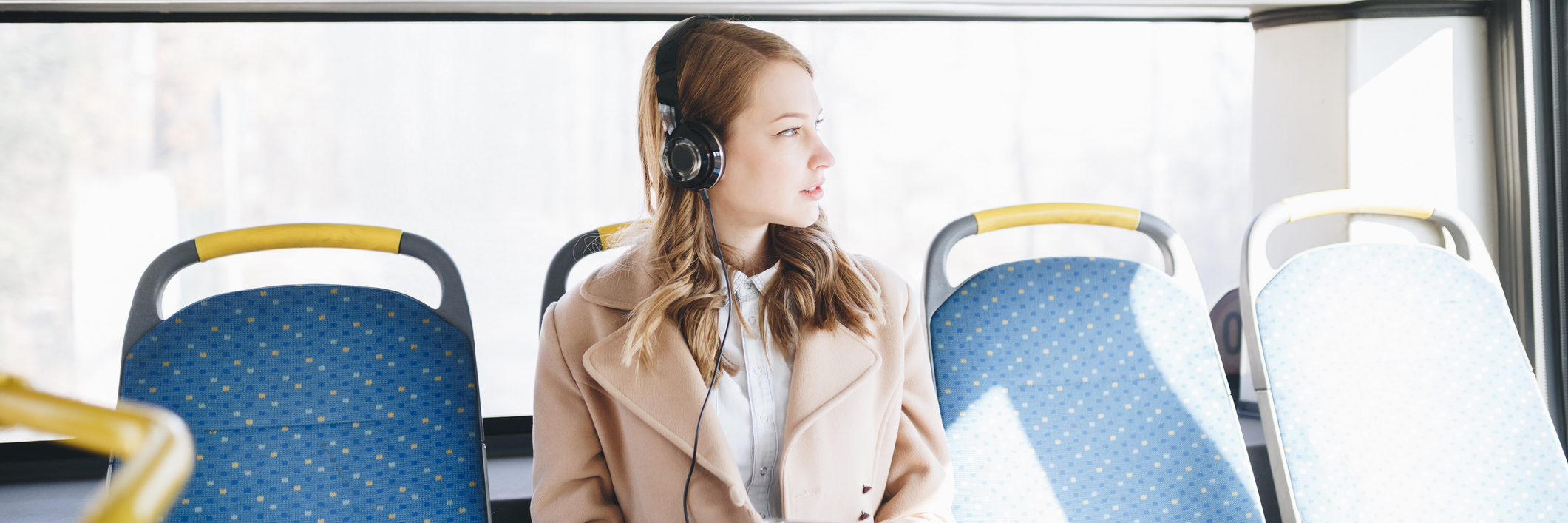 woman sitting on a bus and listening to music