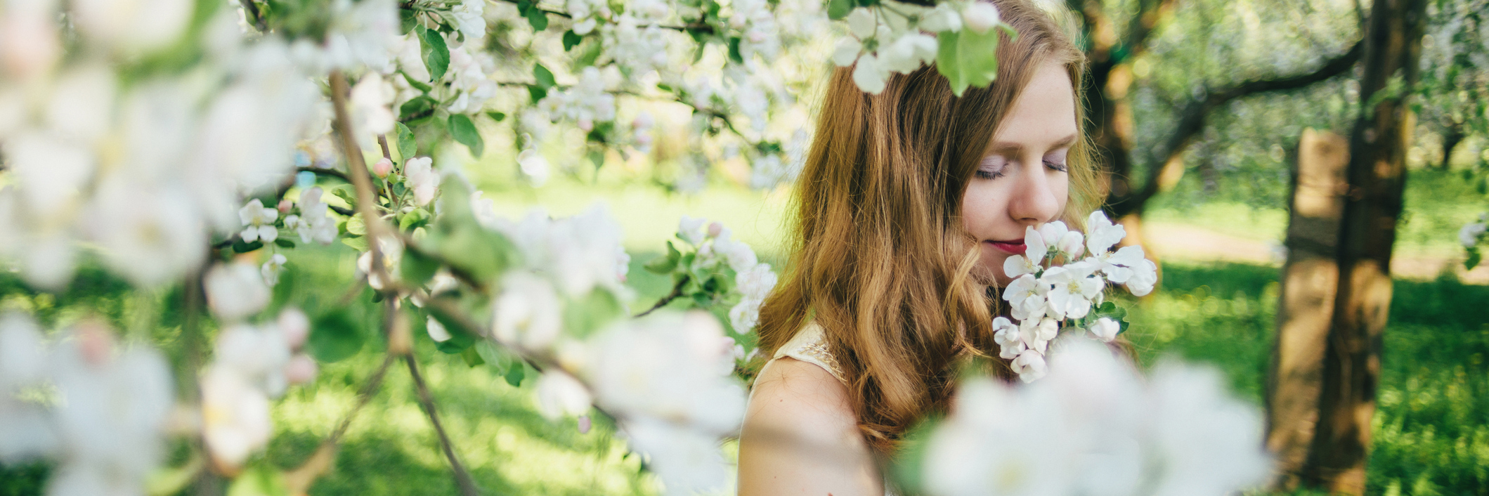 4 Ways I've Grown Because of Arthritis and Lupus A girl in a white dress, in an apple orchard, smelling flowers.