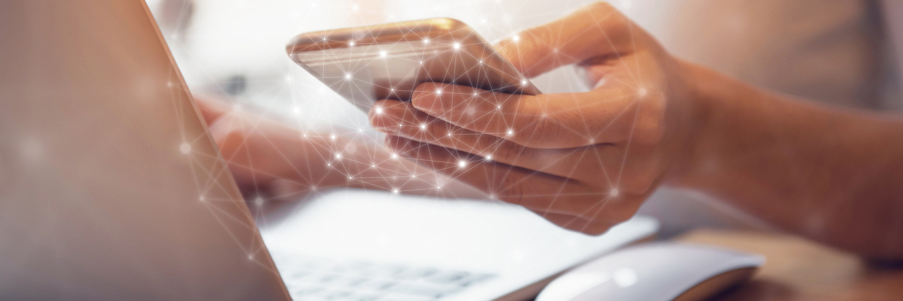 Maintaining Relationships Through Social Media With Chronic Illness woman working on laptop and holding her cell phone