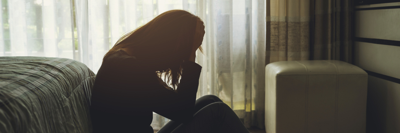 depressed woman sitting in the dark bedroom