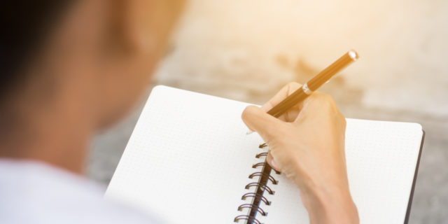 A woman writing somethings in a notebook.