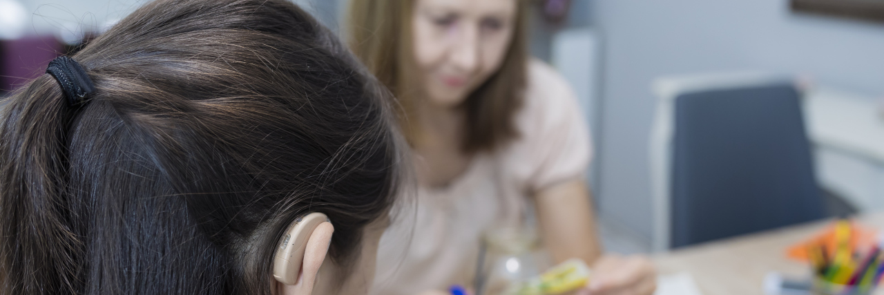 Letter to the Hearing Support Teacher Who Refused to Give Up on Me Girl with hearing aid and her teacher working on a project.