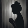 silhouette of a woman standing in front of a grey striped wall