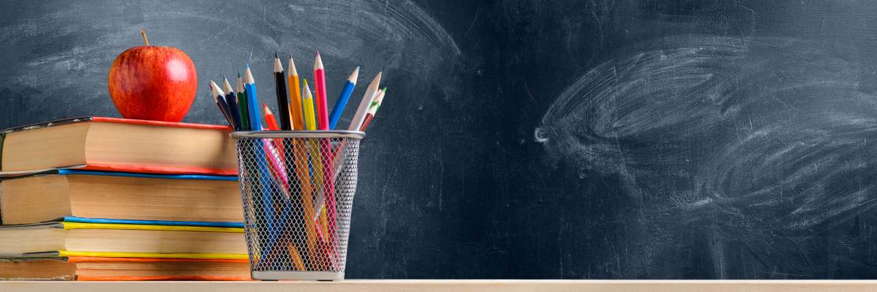 books, apple and pencils next to a chalkboard