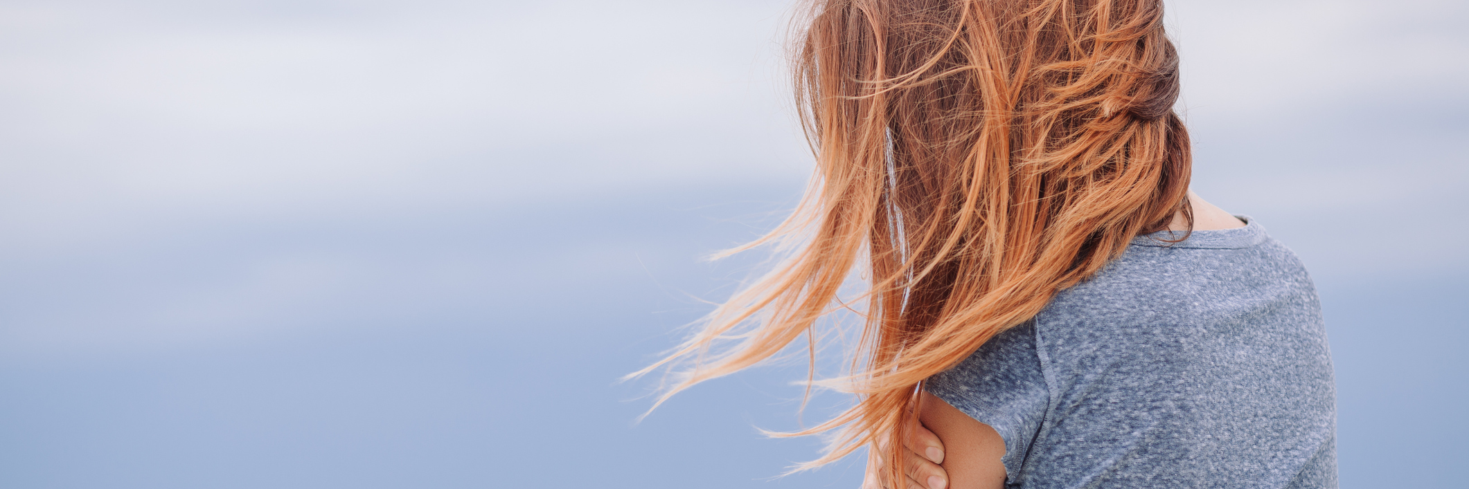 6 Years Later: Living With PTSD From the 2011 Norway Terror Attacks blonde woman holding arms by sea with face covered by hair