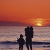 woman with kids on beach during sunset