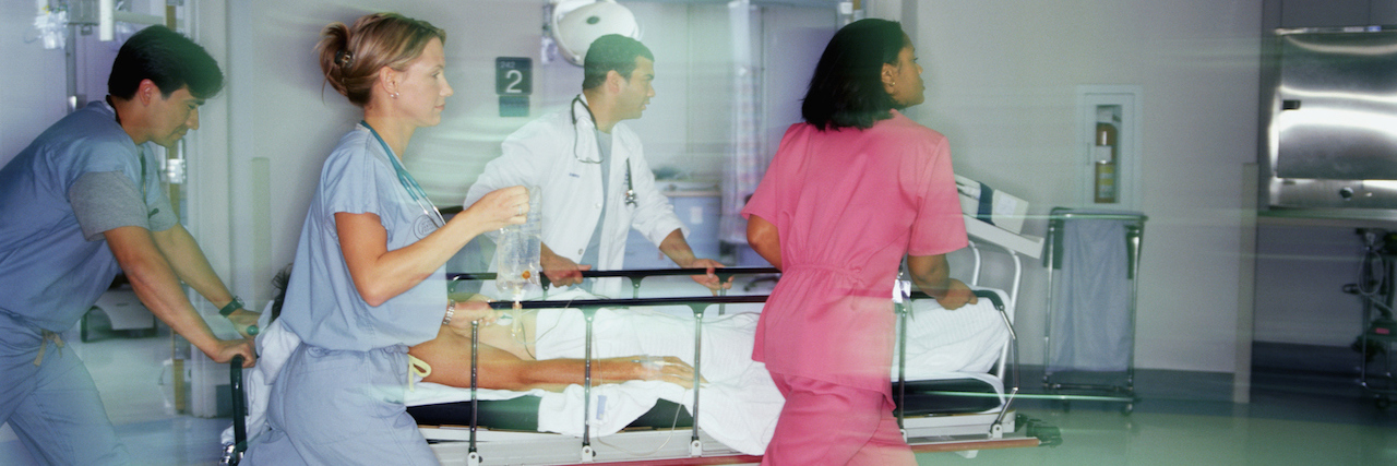 Why the ER Can Be Dangerous for Patients With Eating Disorders Doctors and nurses pushing patient on gurney through emergency room