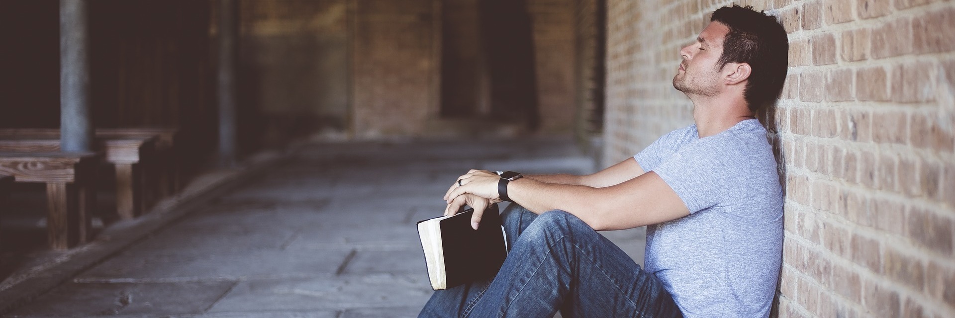 What I Learned Starting My Own Business Despite My Social Anxiety man with back to brick wall holding book