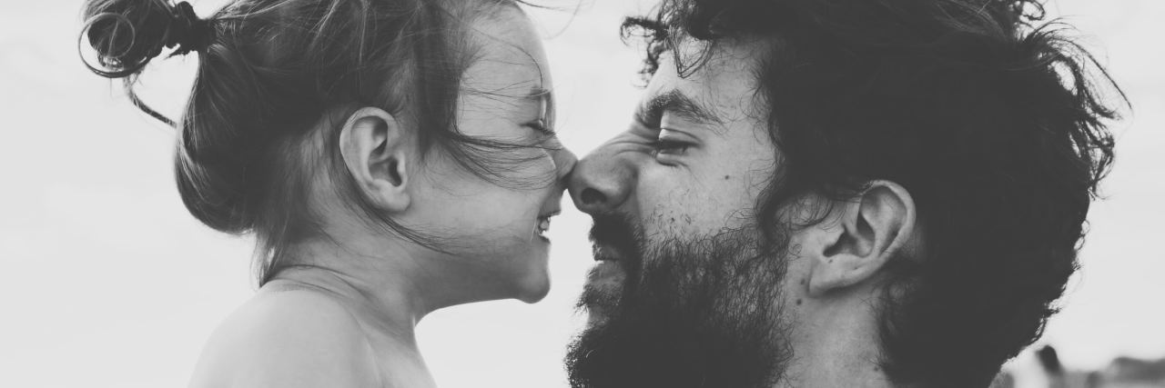 black and white photo of little girl and father nose to nose smiling