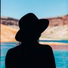 silhouette of a woman against a lake and red hills