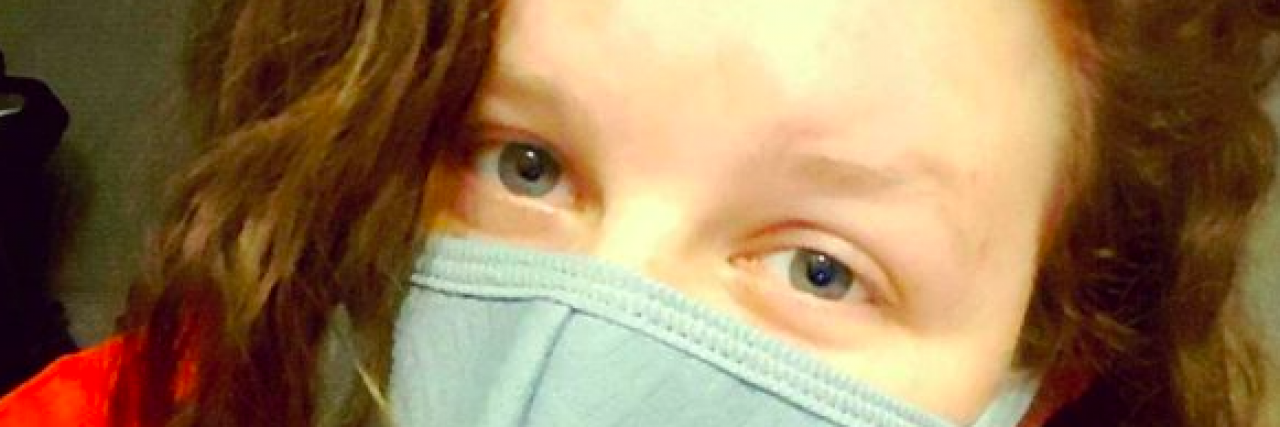 Marisha Dotson Shares Photos After Pimple Turns Out to Be Skin Cancer Woman with curly red hair wearing a face mask