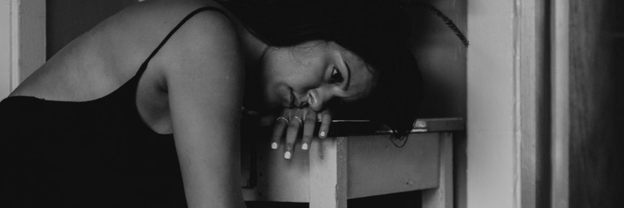 black and white photo of woman with depression leaning against table