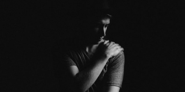 young man in darkness looking depressed anxious