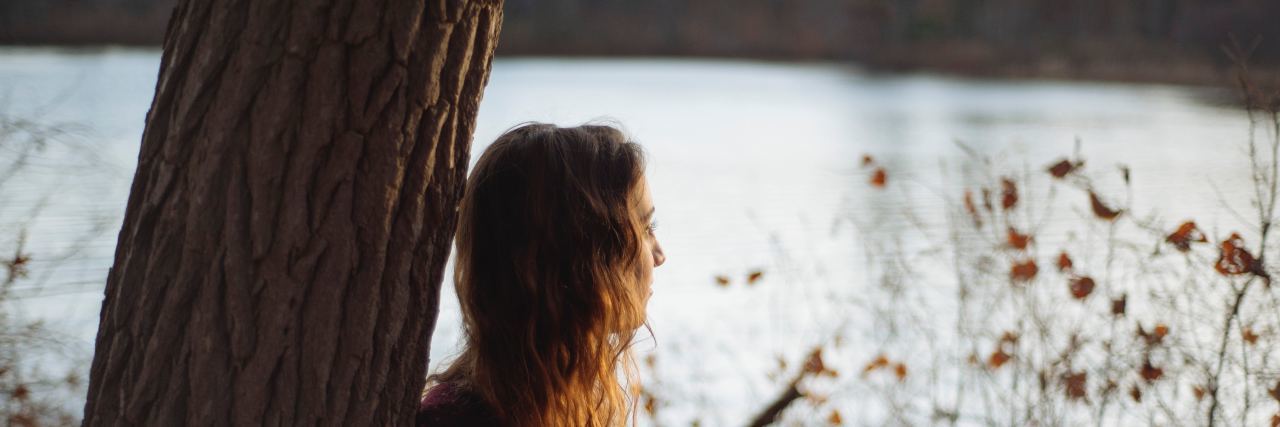 3 Steps in Anorexia Recovery Professionals Don't Talk About a woman stands by a tree overlooking a pond
