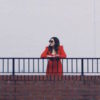 woman in red standing alone along railing