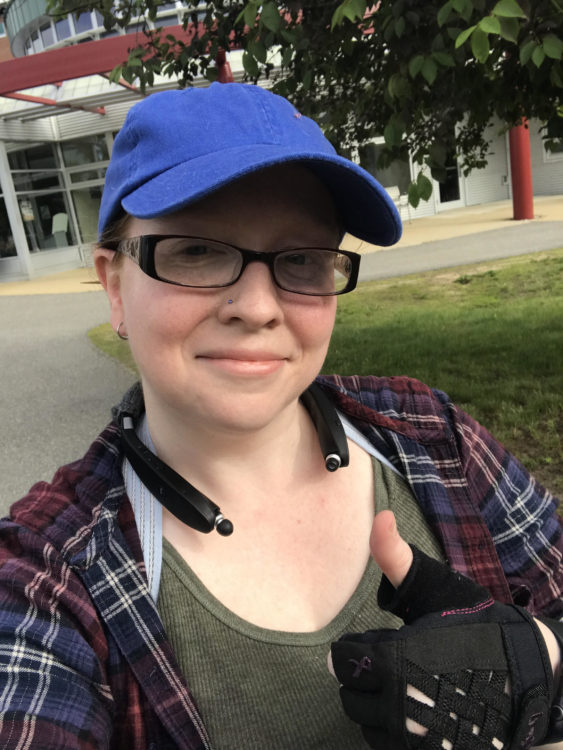 woman wearing a baseball cap and giving a thumbs up