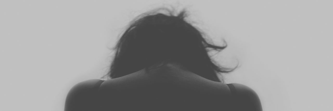 What It Means to Be 'Tired' as Someone With a Mental Illness dark shadow woman looking down