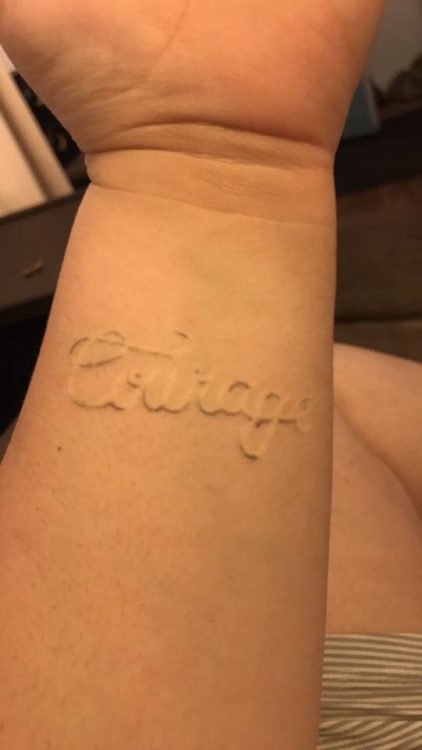 white ink tattoo that says 'courage'