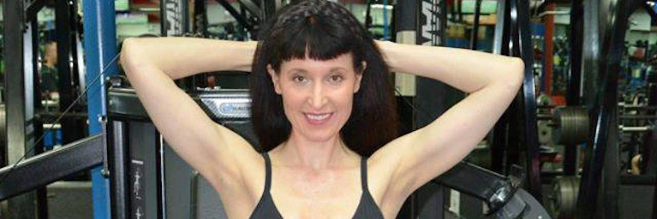 Fitness Tips for People Living With Chronic Illnesses The writer standing by some exercise machines in a gym.