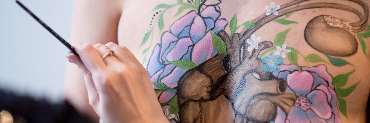Making My Health Struggles Visible to Learn to Accept My Body woman having her body painted