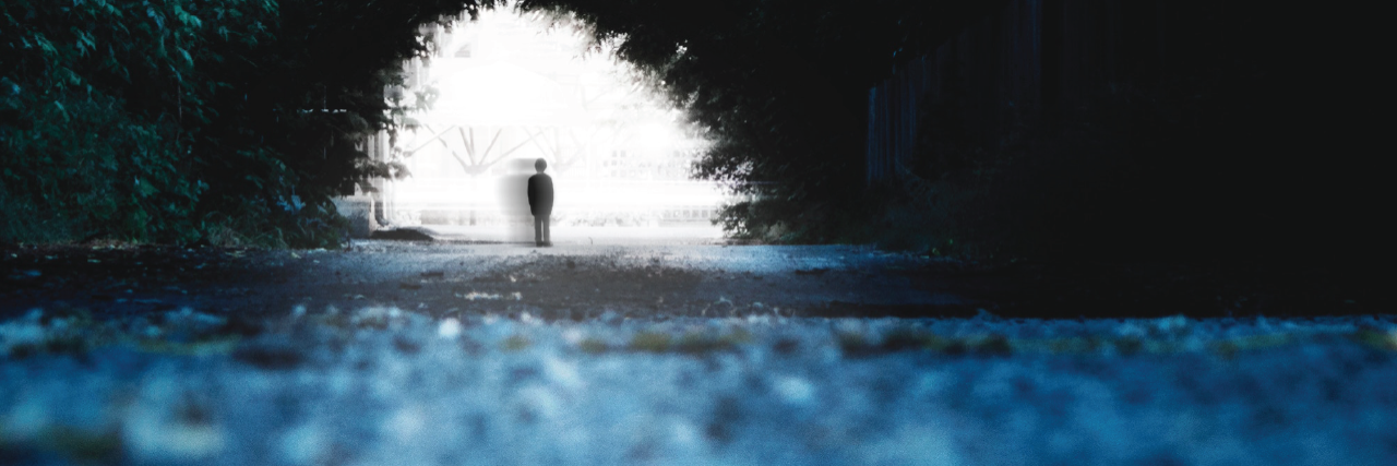 The 32 Worst Symptoms of Mental Illness We Don't Talk About a shadow stands in the light of a long tunnel