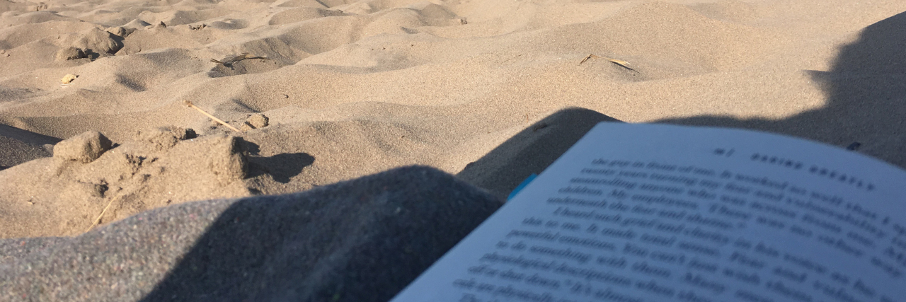 Why Today Was a Win Over My Anxiety close up of book lying on beach in the shade with sea in background