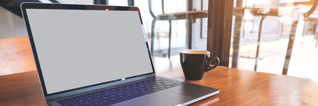 Mockup image of laptop with blank screen on wooden table near by window in modern cafe
