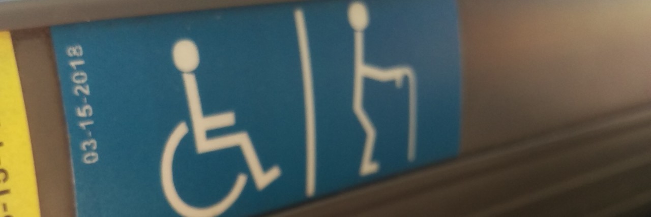 The Blessings and Curses of Growing Up With Chronic Pain Disability sign showing a wheelchair user and cane user.