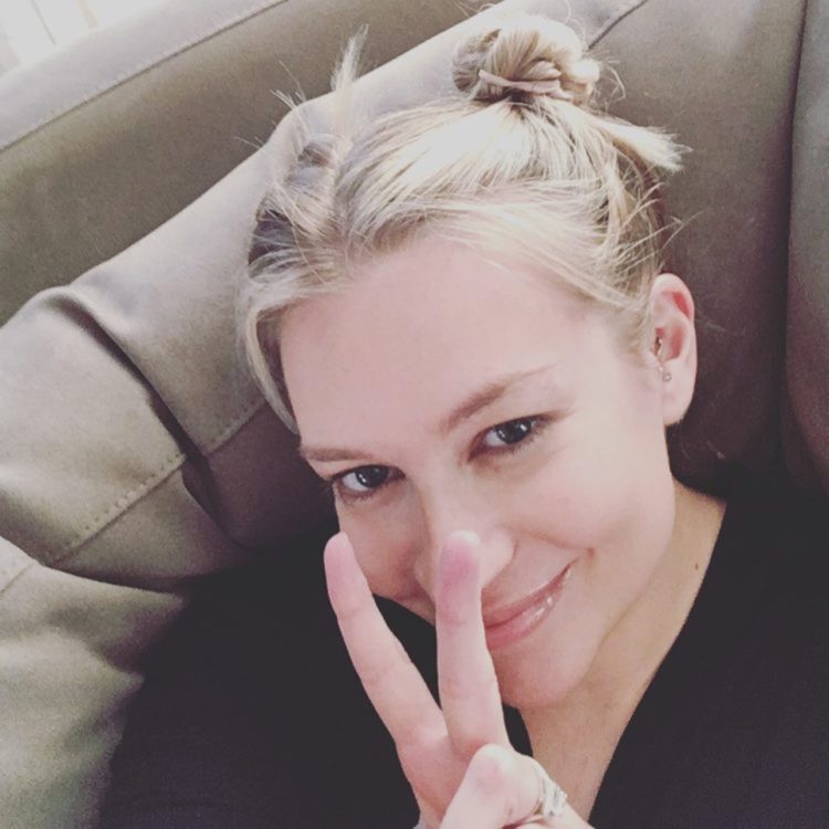 The writer sitting on a couch, making the "peace" sign.