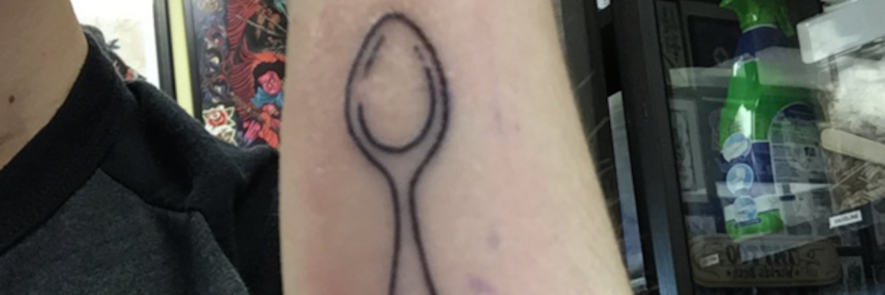 The writer showing her new spoon tattoo on her arm.
