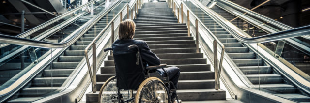 Businessman in a wheelchair against modern stairs.