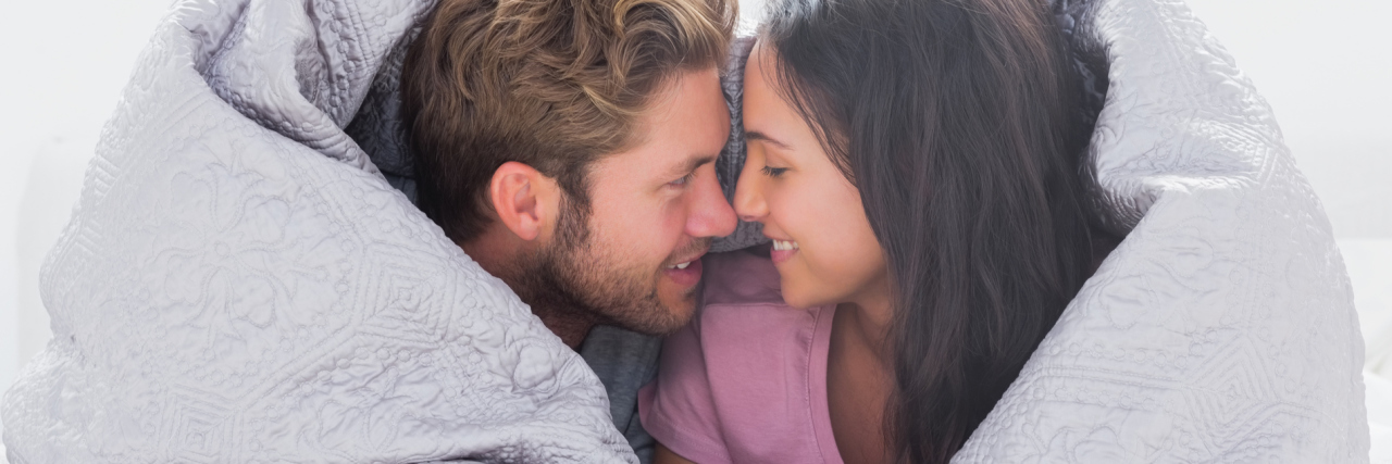 Real Love and Mental Illness: What You Need to Know man and woman in bed under duvet facing each other smiling in love