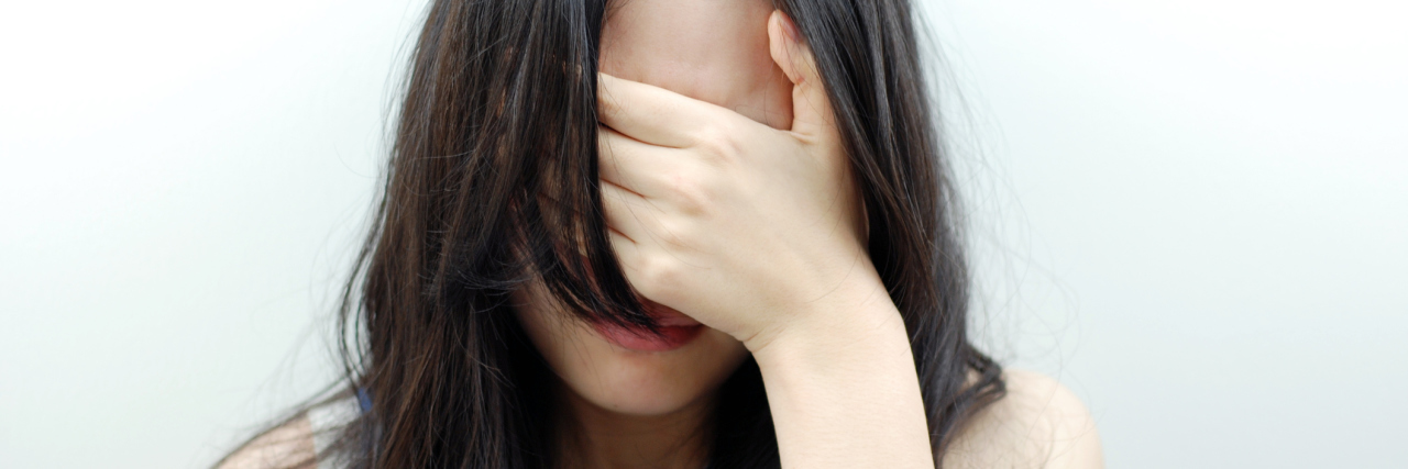 woman covering eyes against unfocused background