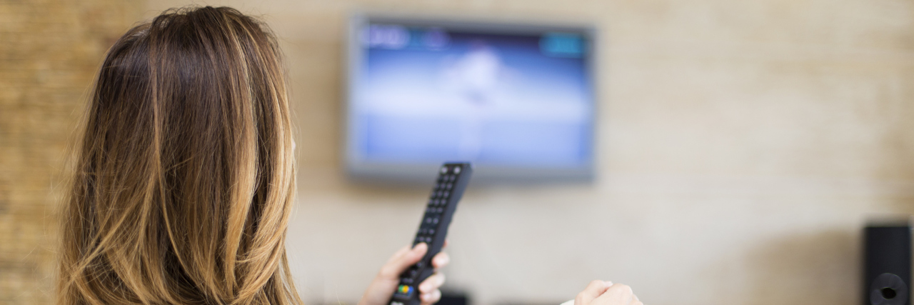 woman watching tv and holding a remote