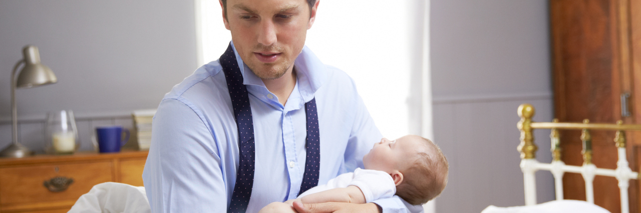 father holding baby in bedroom looking depressed or stressed