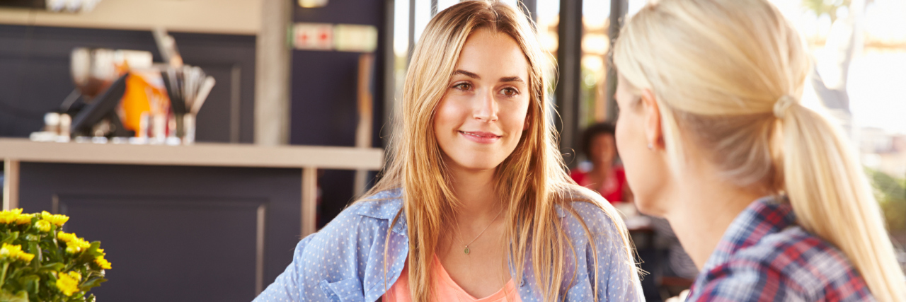 How to Talk to Your Loved Ones With Chronic Pain Two female friends talking in a coffee shop.