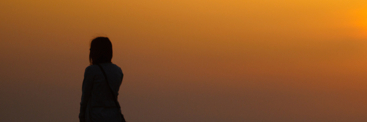 Silhouette of woman in front of sunset sky