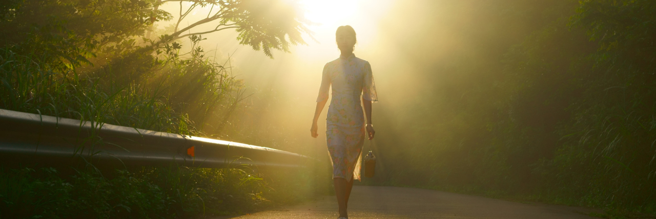 CSF Leak: Coping With the Fears of Chronic Illness woman walking down a trail between trees with sunlight ahead