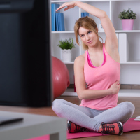 woman doing exercises in front of her tv at home